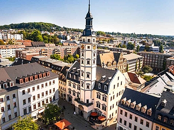 Panoramablick von oben auf den Rathausturm auf dem Marktplatz in Gera, umgeben von strahlendem Sonnenschein und einem klaren blauen Himmel