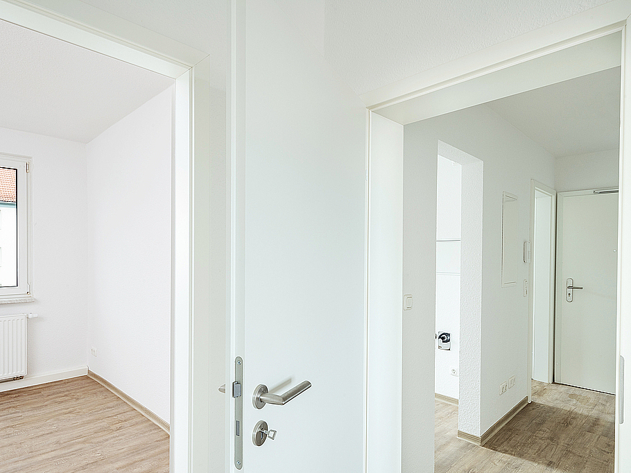 Helle Wohnräume mit modernen Bodenbelägen in Holzoptik und weißen Türen, frisch saniert.