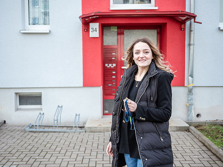 Mit viel Freude dabei, TAG Wohnen Vermieterin Maria vor dem einladenden Mehrfamilienhaus in Stadtilm